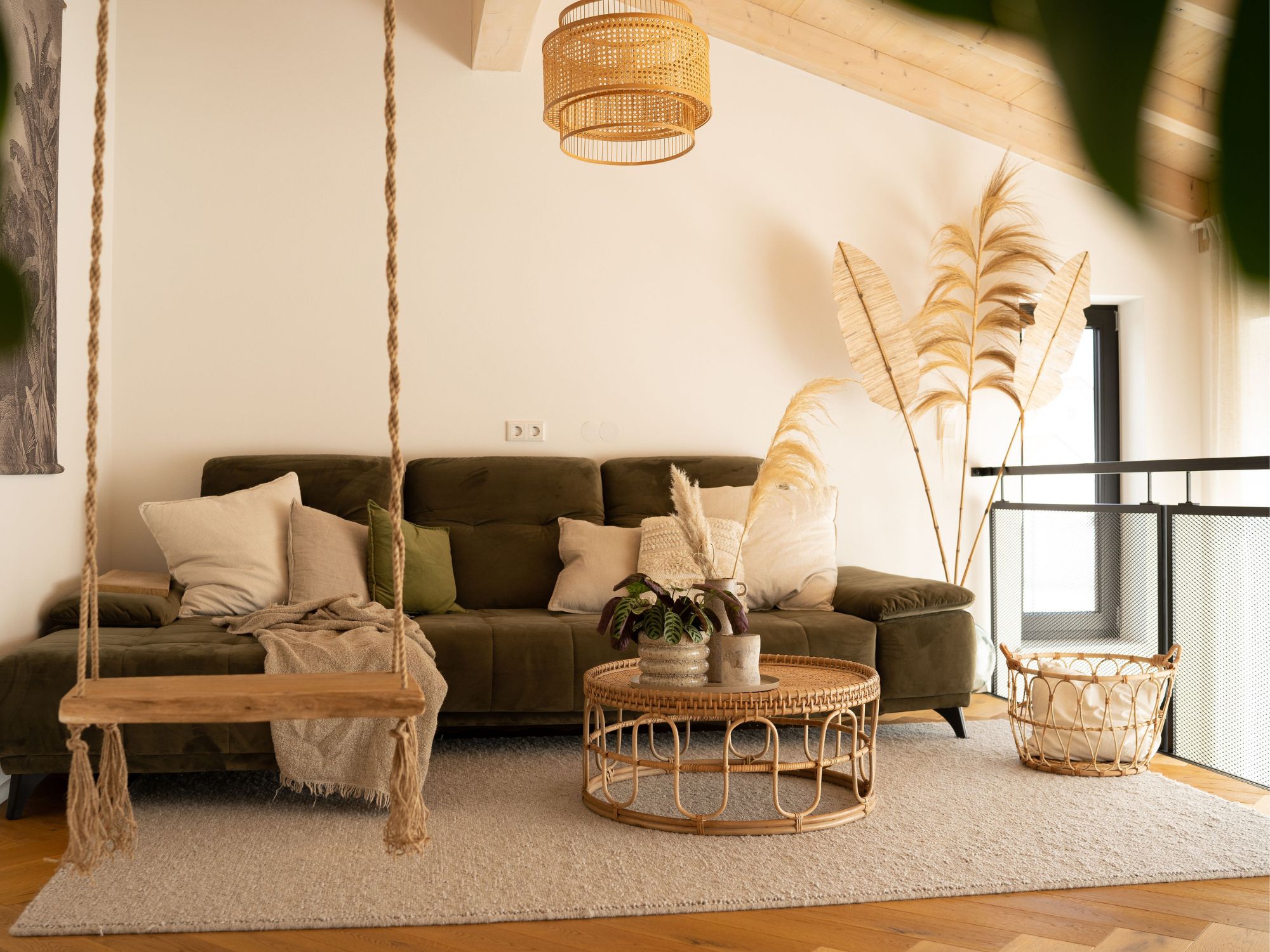 Wollteppich Tarfaya im modernen Wohnzimmer mit grünem Sofa, Hängeschaukel und Naturdeko in warmem Boho-Stil