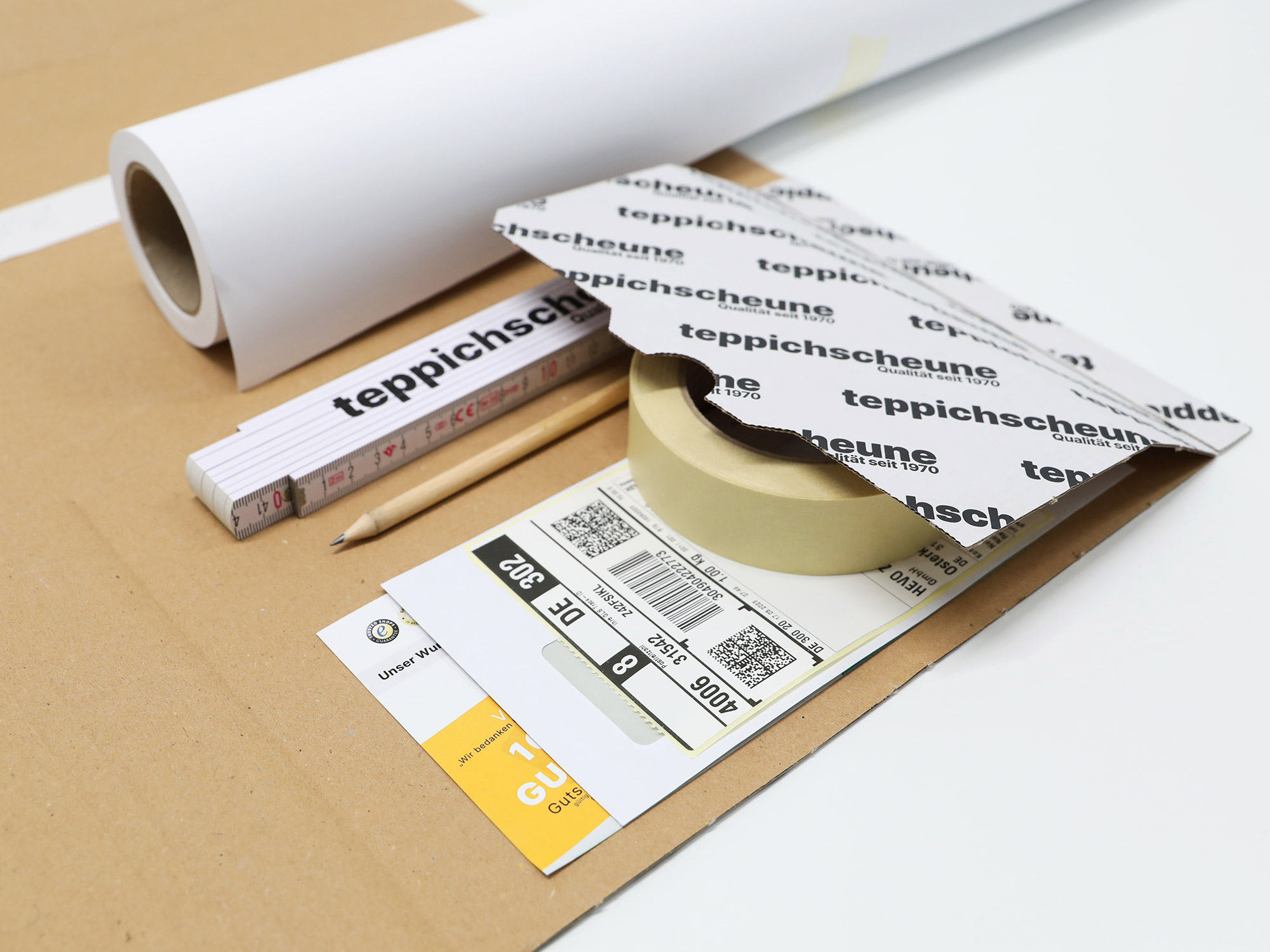 Ruxedo Schablonenset für Wohnmobilteppiche mit Papierrolle, Zollstock, Bleistiften und Anleitung auf einem Tisch