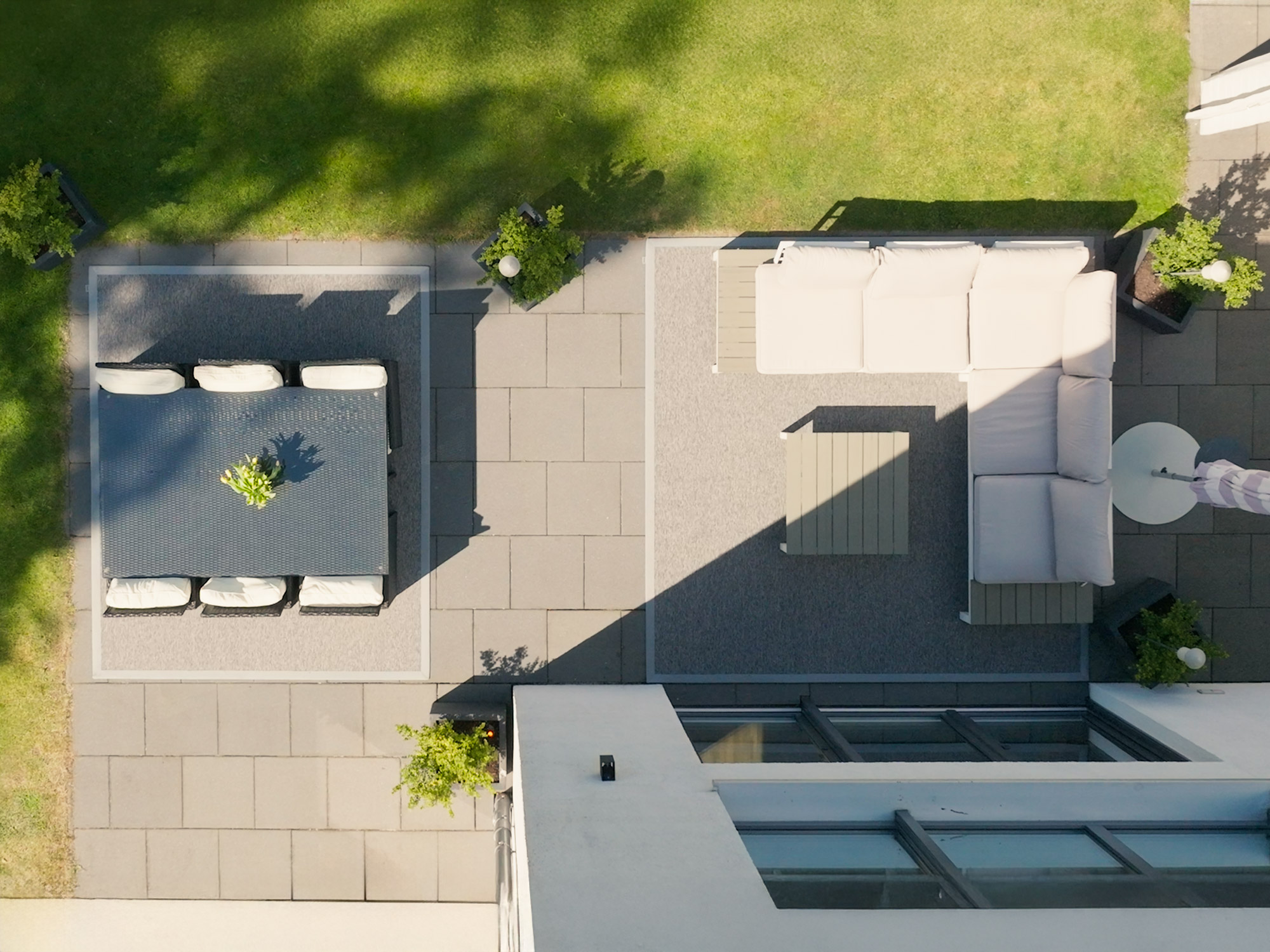 Moderne Terrasse mit zwei rechteckigen Outdoorteppichen von Ruxedo, die Sitz- und Essbereich optisch voneinander abgrenzen – Draufsicht bei Sonnenschein